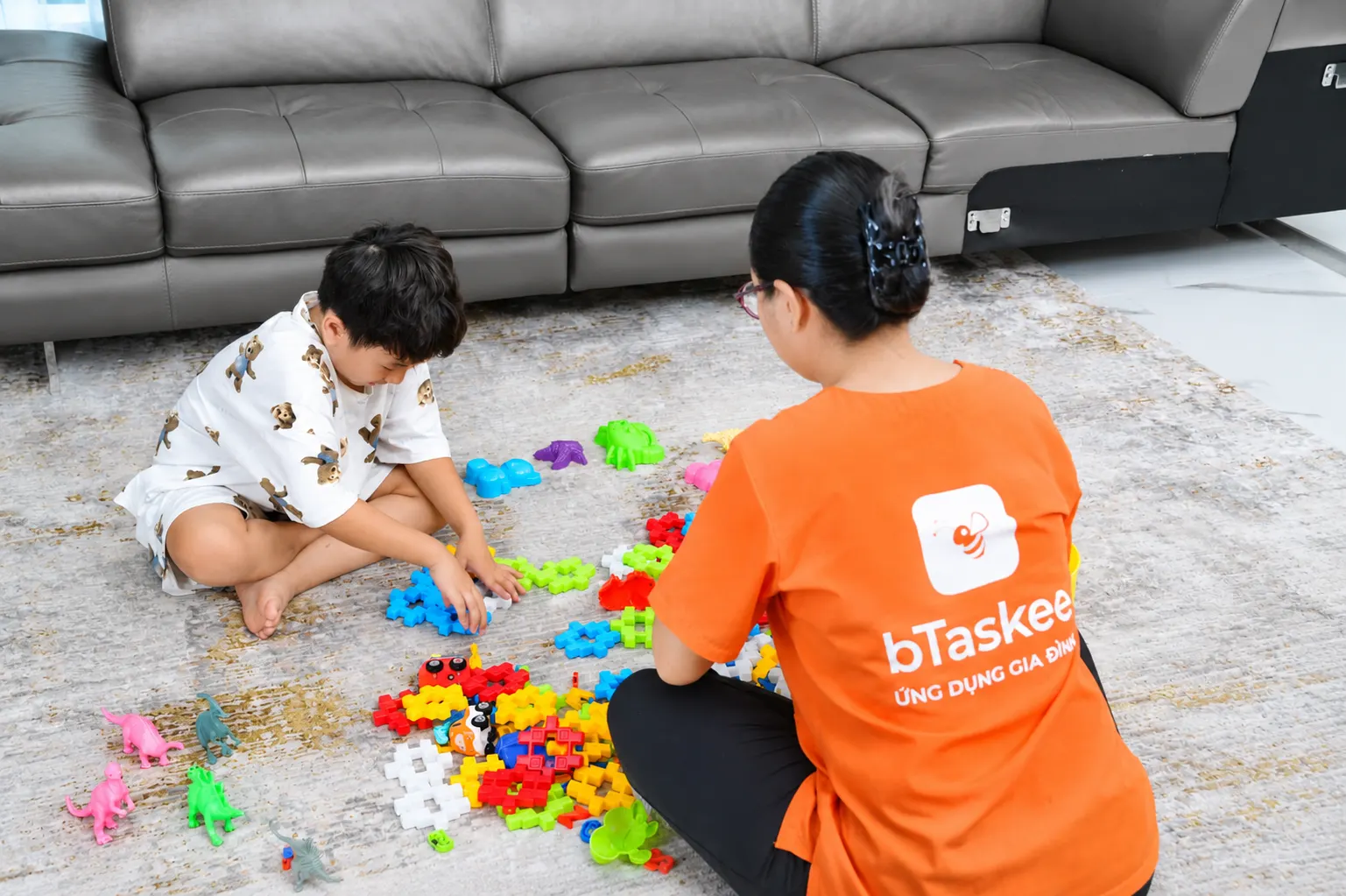 Bé và bảo mẫu chơi đồ chơi trong phòng khách